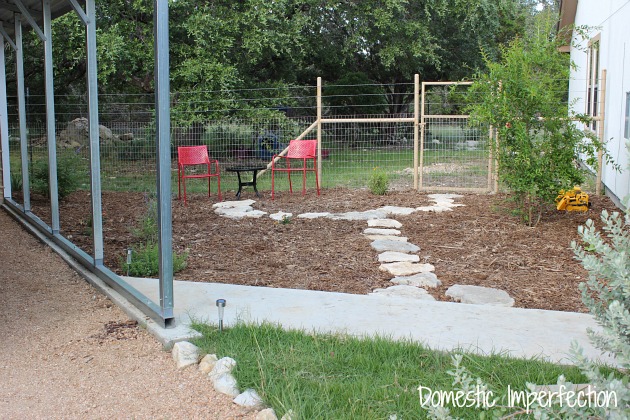 Low maintenance yard with mulch instead of grass, hardy plants, a stone pathway, and seating