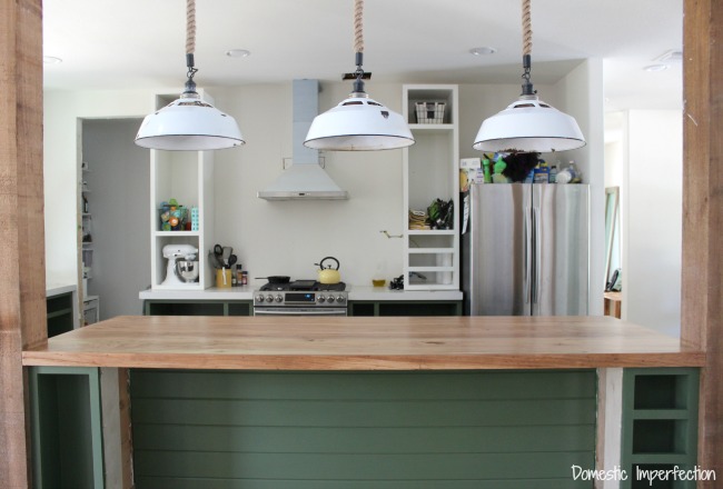 Kitchen Progress – Dark green cabinets, a rustic wood countertop, and lighting