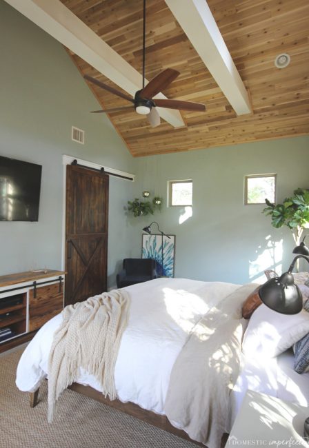 rustic master bedroom with wood ceiling and limestone wall