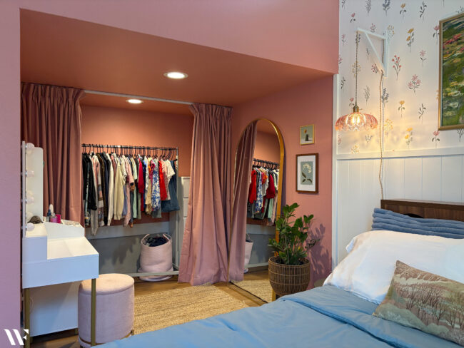 Colorful feminine teen bedroom featuring pink walls, floral wallpaper, blue bedding and functional storage.
