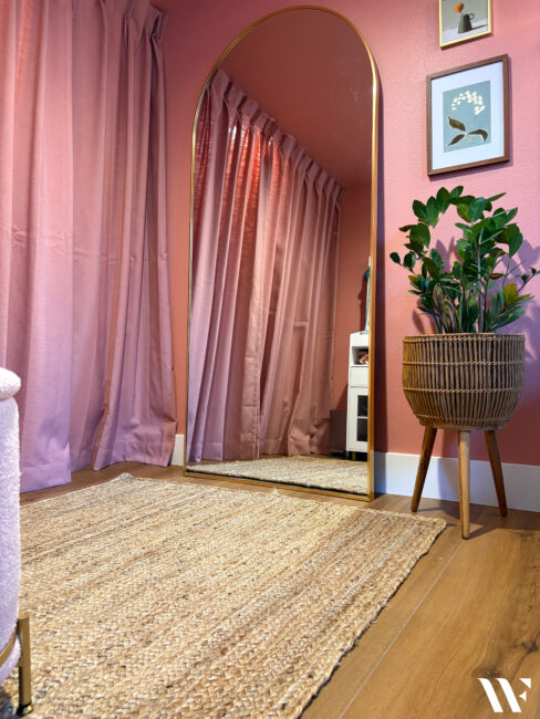 gold arch full length mirror with jute rug and rose pink walls in dressing area