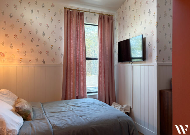 Teenage girl's bedroom makeover with floral wallpaper, pink walls, white paneling and feminine decor.